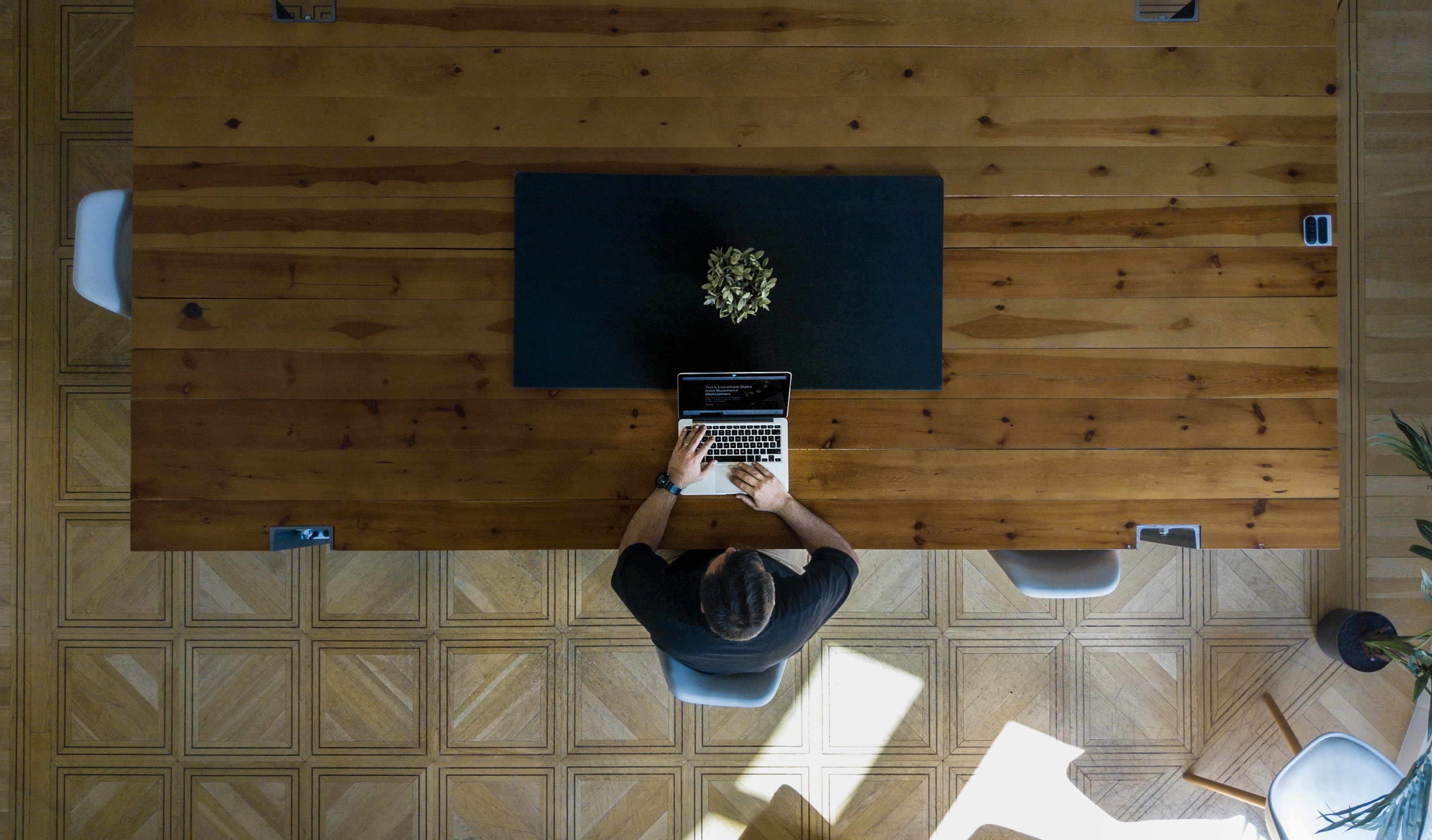 Founder working alone at desk, shot from above sat at a dark wood desk.